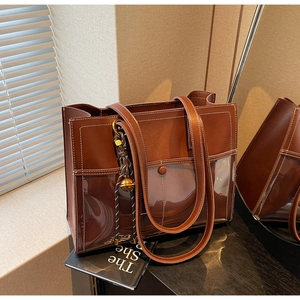 Detailed macro of vintage brown tote bag with leather texture and woven charm accessory
