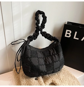 Detail of black quilted nylon tote bag featuring ruched handles and side bow accents