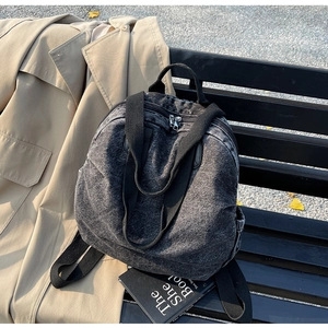 Detail of grey washed canvas backpack featuring wide black straps and double metal zippers
