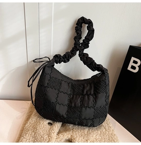 Close-up of black quilted nylon fabric with checkered texture and ruched strap details