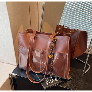 Detail of vintage brown tote bag with PVC pocket, fringe charm and contrast stitching