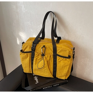 Detail of yellow nylon tote bag featuring front drawstring pocket and metal carabiner clip