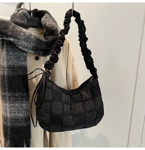 Detail of black nylon tote bag featuring checkered quilted texture and scrunchie strap