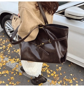 Detail of vintage brown tote bag with metal buckle and adjustable strap in autumn setting
