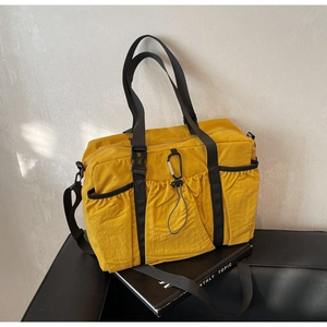 Detailed view of yellow nylon tote bag with utility buckles and elastic drawstrings