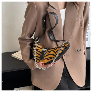 Detail view of tiger print crescent bag with decorative silver chain and leather strap