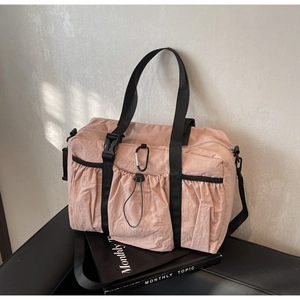 Close-up of pink nylon tote bag featuring durable black straps and drawstring pocket