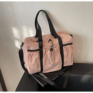 Detail of pink nylon tote bag with drawstring pocket, carabiner, and black straps