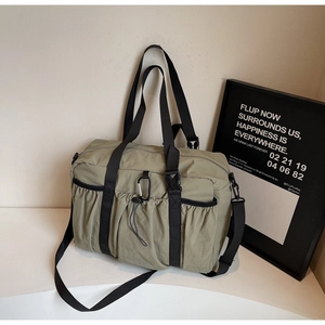 Detail of sage green nylon tote bag featuring functional pockets and adjustable straps
