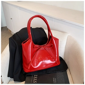 Close-up of shiny red patent leather handbag with bow detail and embossed lettering