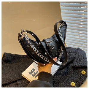 Detail of black faux leather dumpling bag with crocodile pattern and silver chain strap