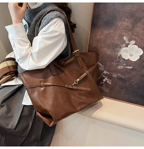 Close-up of a brown vintage tote bag with decorative leather straps and metal buckles