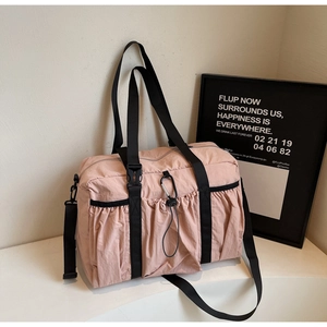Detail of pink nylon tote bag featuring front drawstring pocket and metal carabiner clip