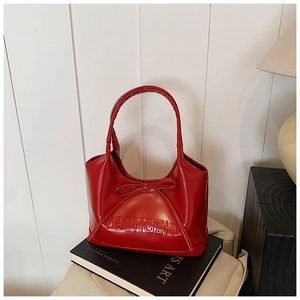 Detail of red leather handbag with bow and embossed logo on an art book setting