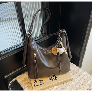 Detail of deep brown Hobo bag featuring glossy leather and a creative baseball charm