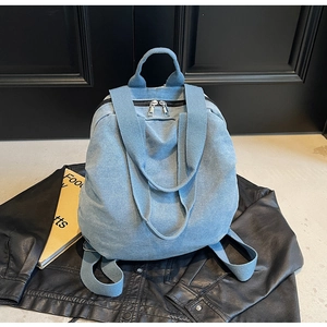 Detail of light blue denim backpack showing dual metal zippers and durable canvas texture