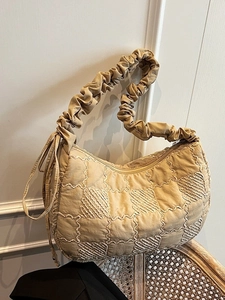 Fashionable beige nylon pleated tote bag with checkerboard stitching on a woven chair