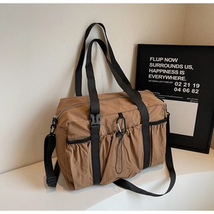 Detail of a large brown utility bucket bag showing buckle straps and side pockets