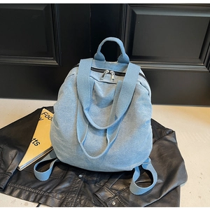 Detailed view of light blue denim backpack with sturdy straps and metal zipper detail
