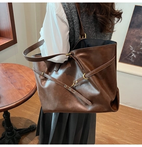 Detail of vintage brown leather tote bag showing crossbody strap and metal ring buckle