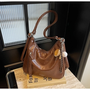 Detail of vintage brown leather hobo bag with baseball charm and side zipper pocket