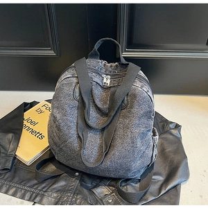 Detail of grey washed denim backpack featuring thick silver zippers on black leather