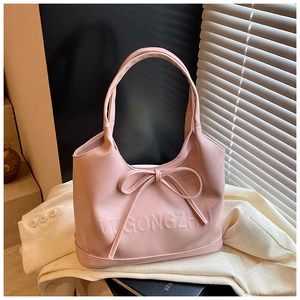 Close-up of pink handheld bag with a decorative bow and embossed brand detailing