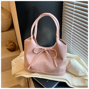 Detail shot of a pink handbag with a large bow and VUGONGZHU embossed logo lettering