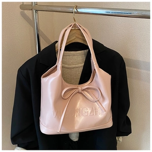 Close-up of pink shoulder bag featuring a decorative bow and textured leather logo detail