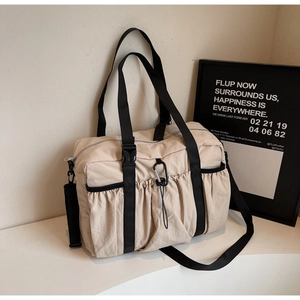Macro detail of beige nylon tote bag featuring black buckles and adjustable strap