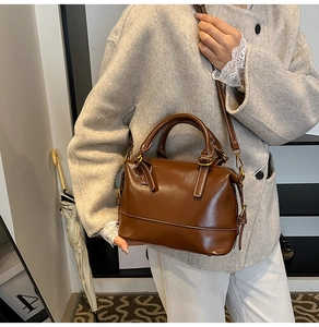 Close-up of a vintage brown leather Boston bag with shiny texture and top handles