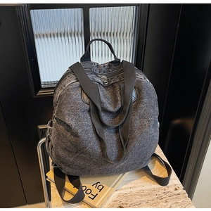 Close-up of vintage washed denim backpack featuring metal zippers and side pockets