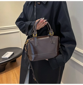 Detailed close-up of dark brown glossy leather handbag with vintage bronze hardware