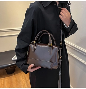 Detailed side view of a vintage dark brown Boston bag with glossy finish and top handles