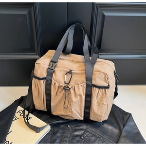 Detail of khaki nylon tote bag with black woven handles and carabiner clip attachment