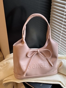 Chic light pink faux leather tote bag with embossed text and elegant bow accent