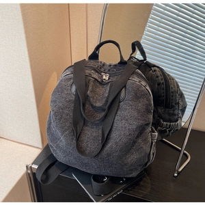 Detail of washed grey denim backpack with adjustable straps and side elastic pocket
