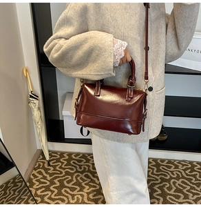 Detailed shot of a burgundy glossy pillow bag with golden hardware and leather top handle