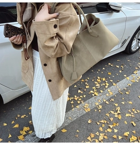 Close-up of matte suede tote bag with side shoulder strap view and square pendant