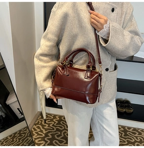 Detail of dark red oil wax leather Boston bag showing glossy texture and gold hardware