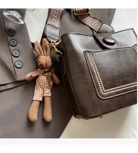Detalle de bolso cubo retro marrón oscuro con remaches y correa ancha étnica