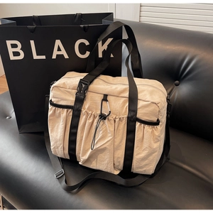 Detail of light beige nylon tote bag with black wide straps and climbing buckle hardware