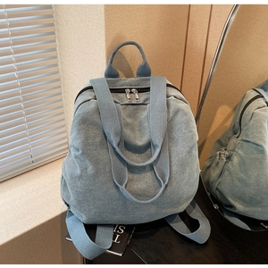 Detailed view of the blue denim backpack with sturdy handles and side storage pockets