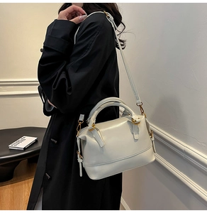 Detail of cream white leather boston bag with golden hardware and adjustable shoulder strap