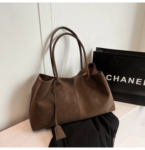 Detail of deep brown suede tote bag showing vertical stitching and matte texture