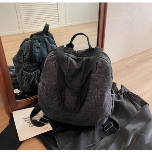 Macro detail of the dark wash denim backpack with adjustable straps and side pockets