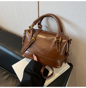 Detail of vintage brown oil wax leather Boston bag with golden hardware and handles