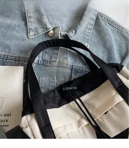 Dettaglio della borsa tote in nylon con chiusura a coulisse e manici in fettuccia nera