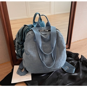 Detailed view of the denim blue backpack showing dual zippers and sturdy canvas texture