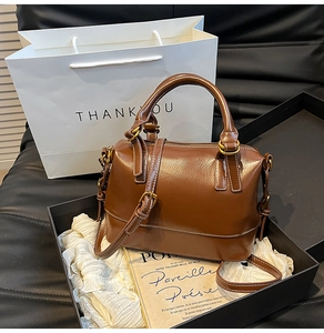 Close-up of brown leather boston bag with bronze hardware and adjustable shoulder strap